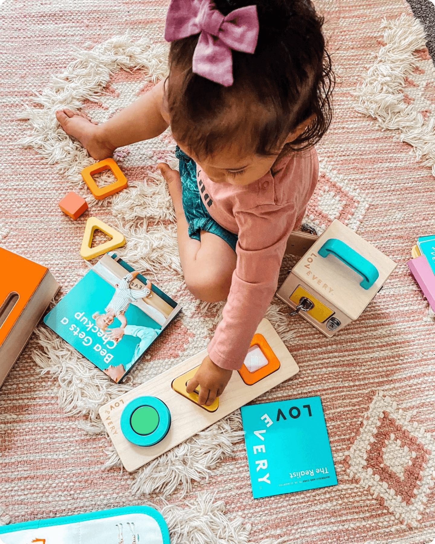 Child playing with several playthings from The Realist Play Kit